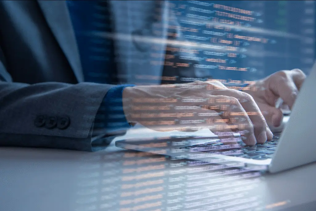 Person arbeitet an einem Laptop mit eingeblendetem Programmiercode.